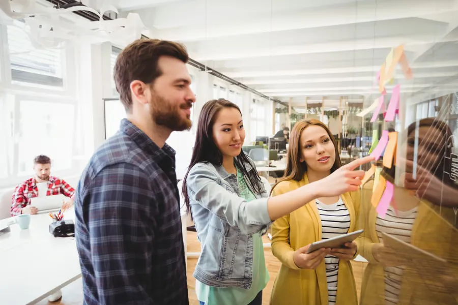 Des collègues échangent leurs idées devant un tableau de notes